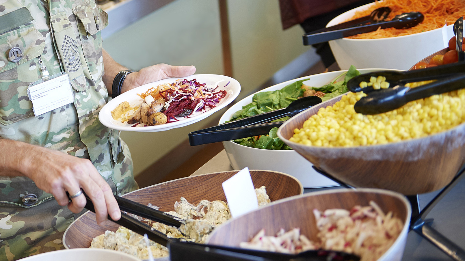En af Forsvarets ansatte er igang med at tage mad fra en buffet i en kantine