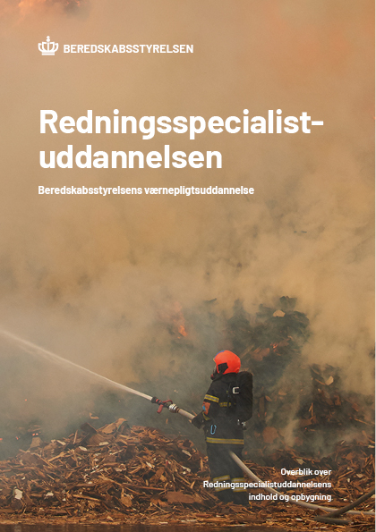 Brandmand bekæmper ild omgivet af røg og murbrokker under træningsøvelse for Beredskabsstyrelsens redningsspecialistuddannelse.