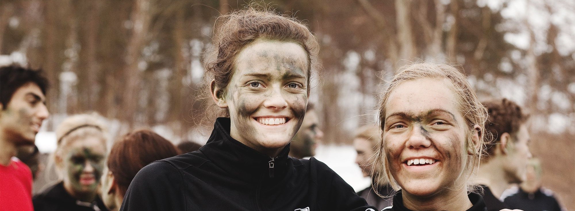 to piger med grøn sløring i ansigtet griner til kameraet