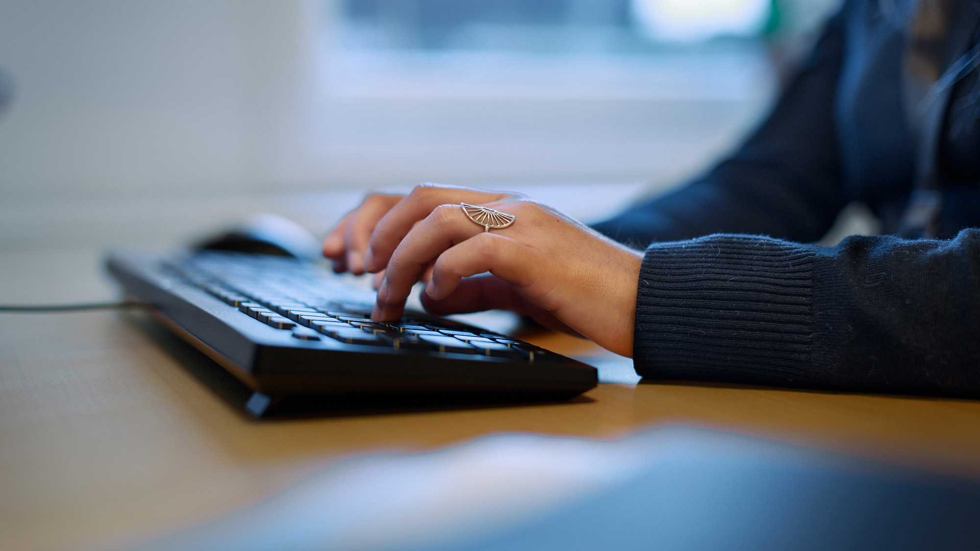 Kontormiljø og nærbillede af hænder der skriver på et keyboard