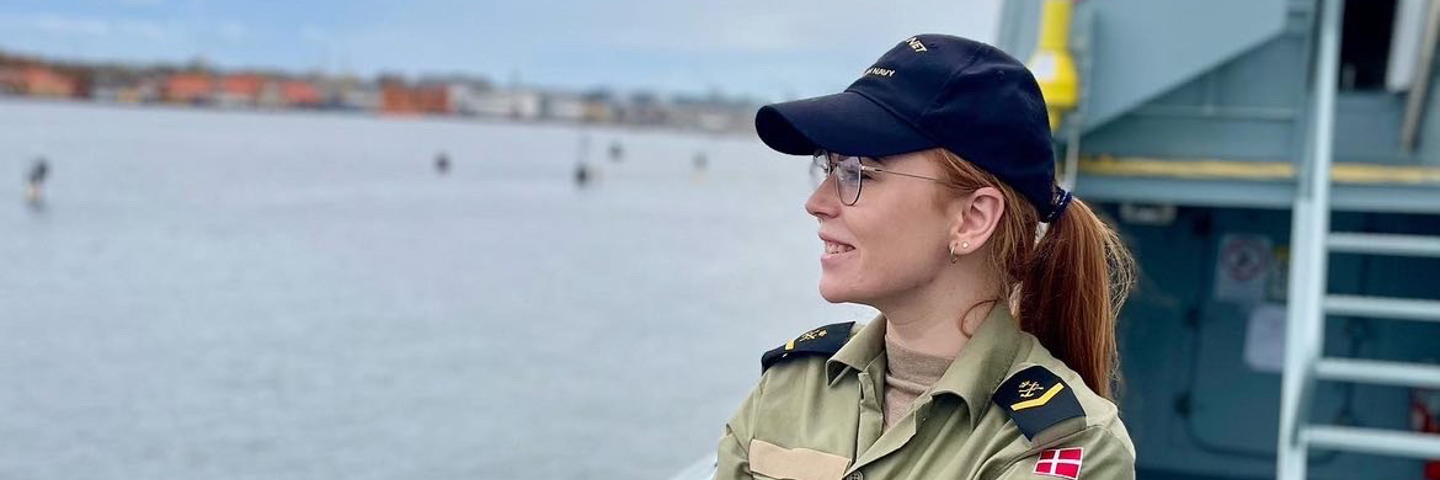 Kommunikationsgast Ida står på dækker og kigger ud over vandet