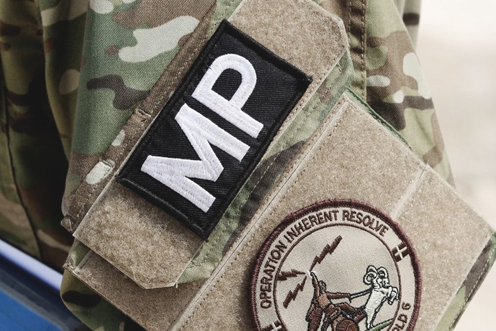 Dansk militærpolitimand med Operation Inherent Resolve-mærke og Dannebrog på camouflageuniform under international mission.