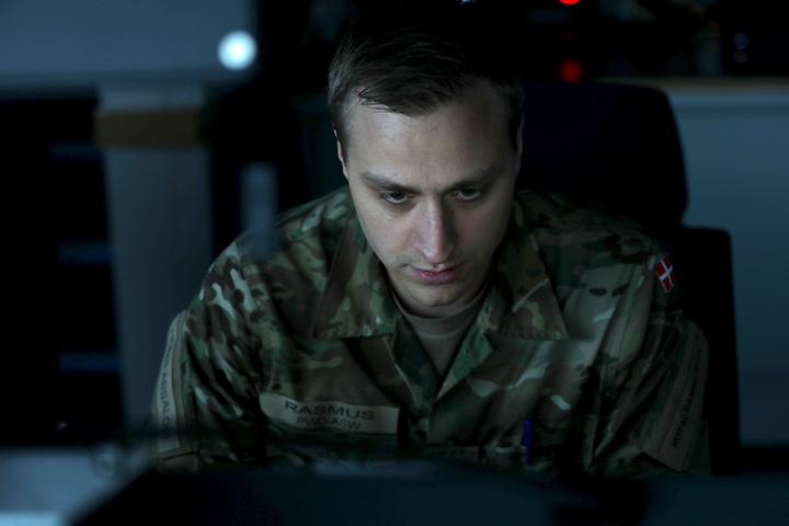 Morten sidder med front mod kameraet og kigger ned i en skærm. Lyset er dæmpet.