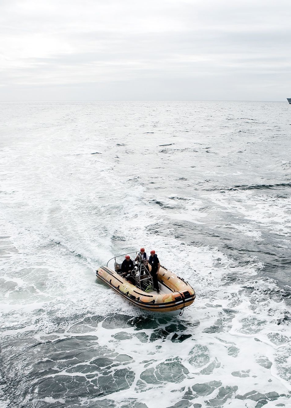 Tre personer i militærtøj og hjelm sejler i en gummibåd på åbent hav under en øvelse med Søværnet.