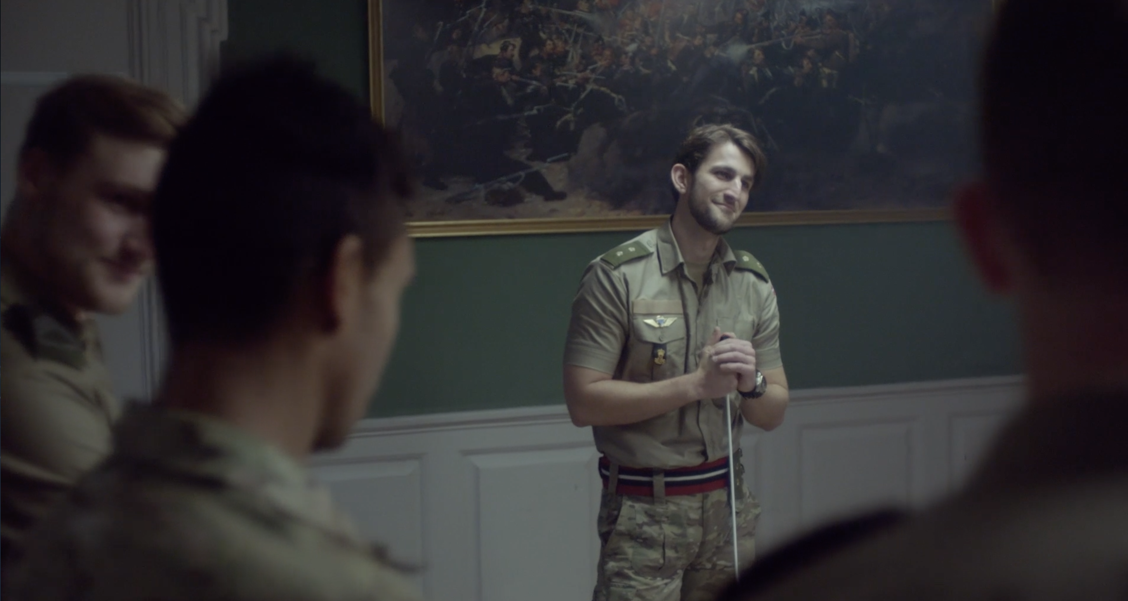 En officer taler til en gruppe soldater i et undervisningslokale.