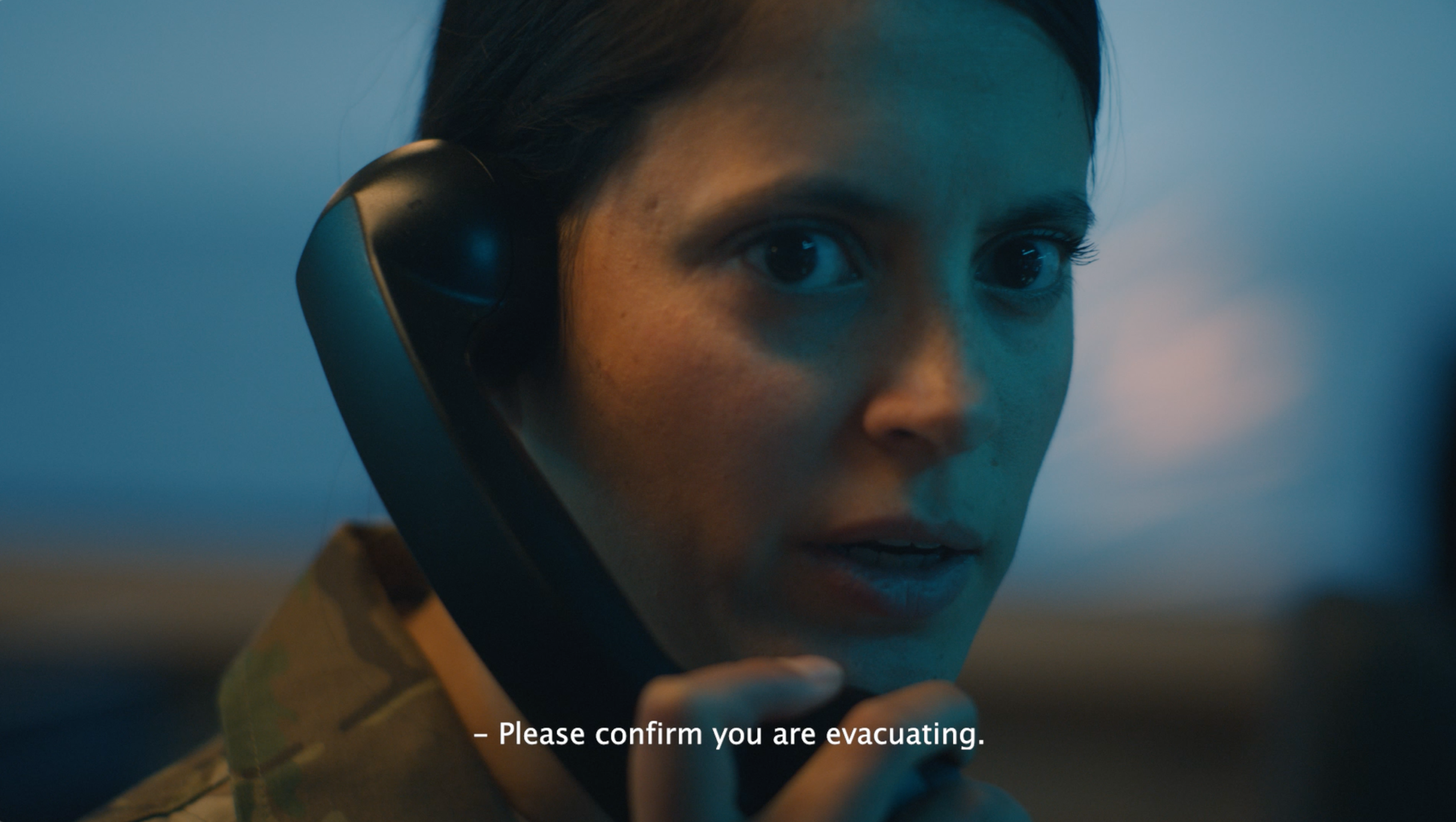 Kvinde i militæruniform taler i telefon med alvorligt udtryk