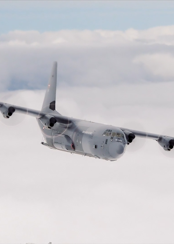 Et dansk C-130 Hercules transportfly flyver over skyerne.
