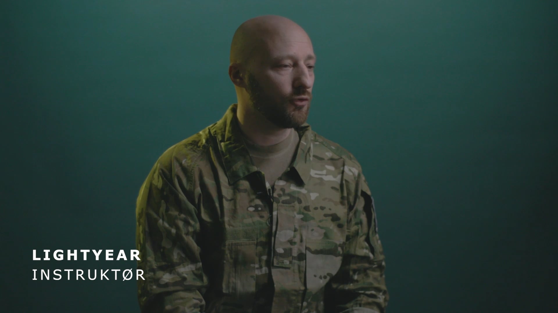 Instruktøren Lightyear i militæruniform taler foran mørk baggrund.