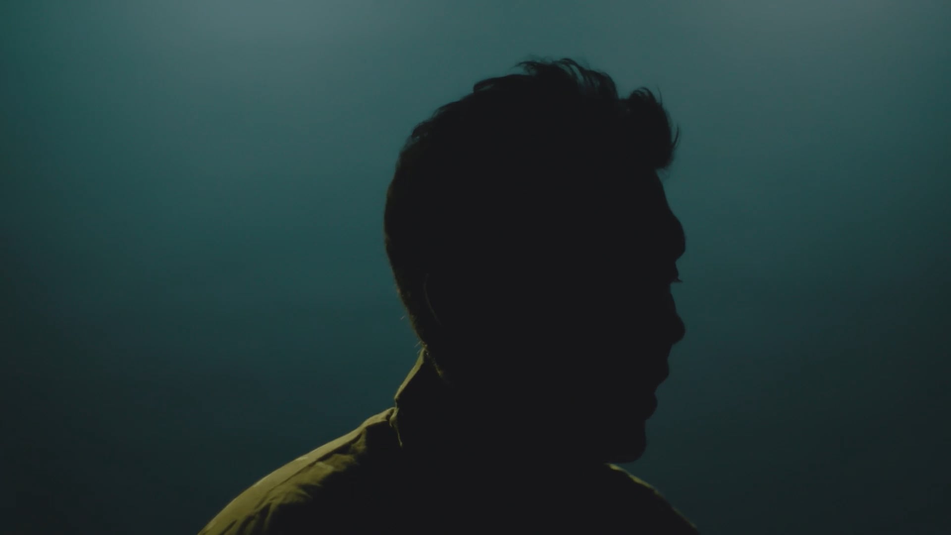 Silhuet af person i profil mod mørk baggrund.